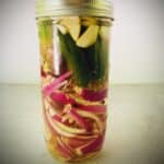 tall mason jar filled with completed red onion pickles.