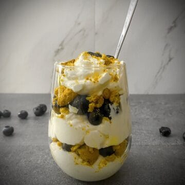 5 minute blueberry lemon dessert trifle in a stemless wineglass with a silver spoon sticking out of it.