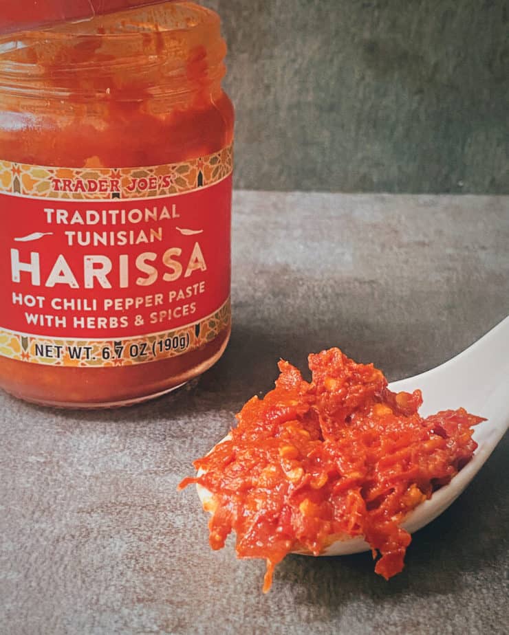 A close up of a spoonful of bright red, beautifully bold harissa