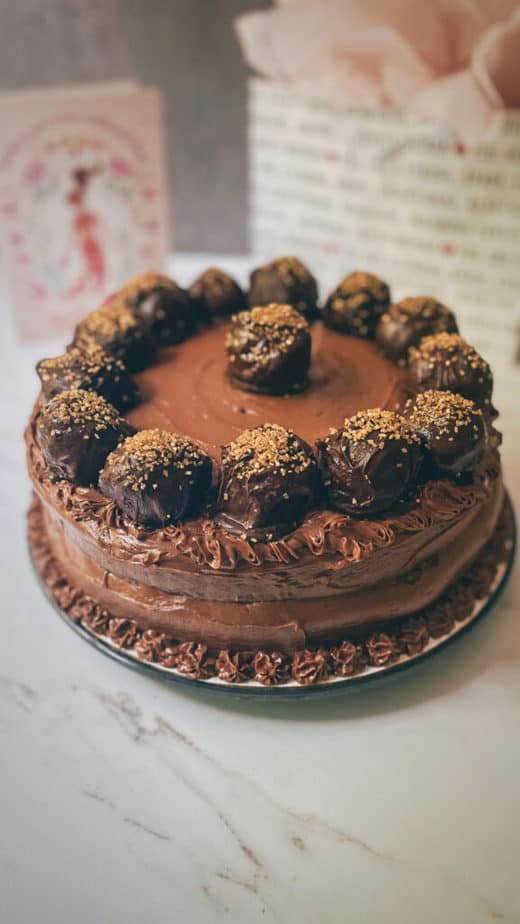 a 45 degree angle portrait shot of my vegan flourless chocolate truffle cake with presents in the background