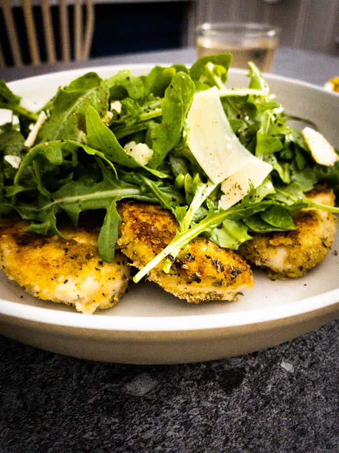 Very close up shot of paillards topped with arugula salad