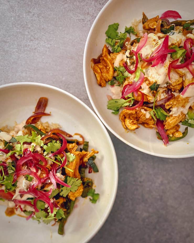 Overhead shot of HelloFresh's Yucatan Citrus Chicken Bowls in tan colored pasta bowls with grey concrete backdrop