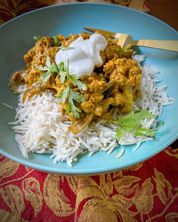 hero shot of vegan cauliflower tikka masala over basmati rice in a turquoise bowl on a fall themed dish towel