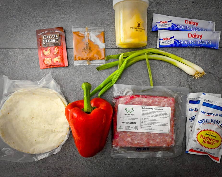 Overhead shot of pineapple chunks, green onions, sour cream, bbq sauce, ground pork, red bell pepper, flour tortillas and seasoning packets from my home chef review
