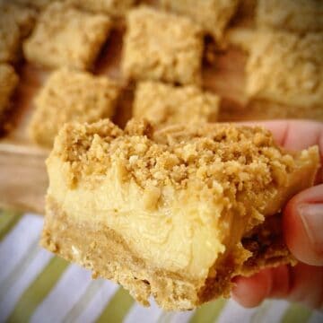 square shot of hand holding a coconut ginger key lime bar.