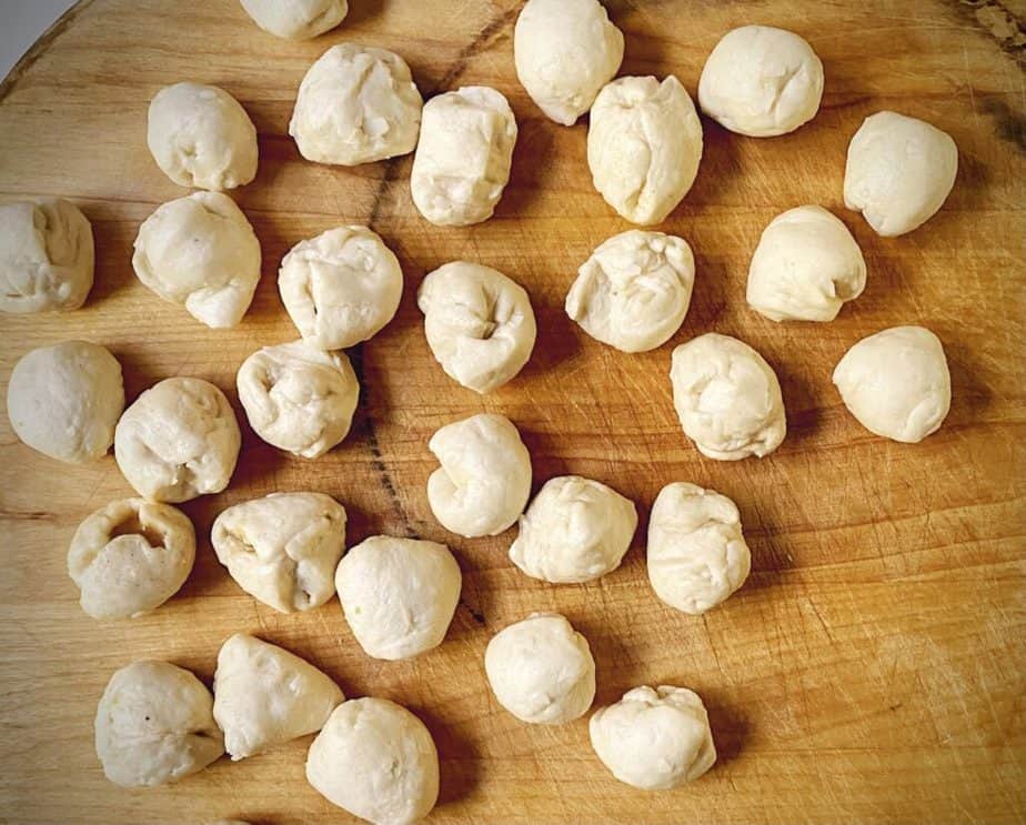 filled biscuit dough that has been rolled into balls on a wooden cutting board