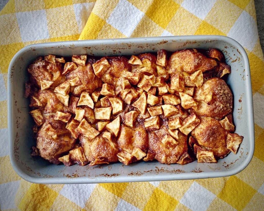 completed cinnamon apple monkey bread in the tin on a yellow and white gingham tea towel