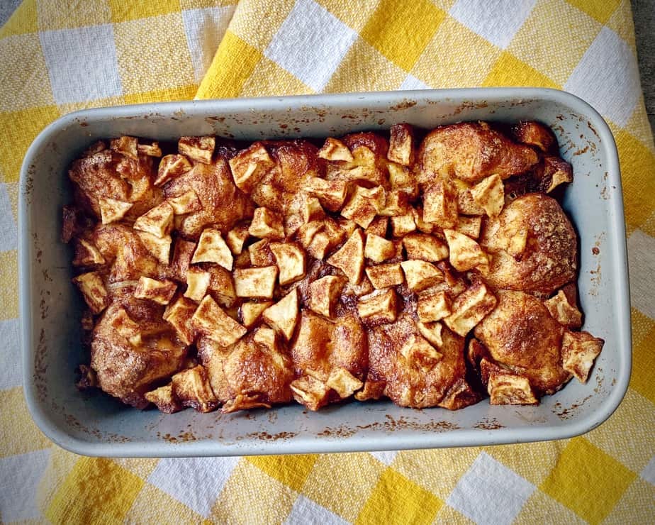 completed apple cinnamon monkey bread in a loaf pan on a yellow and white gingham tea towel