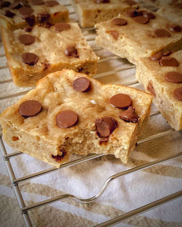 up close 45 degree angle shot of a bite taken out of a healthy banana chocolate chip breakfast bar on a cooling rack