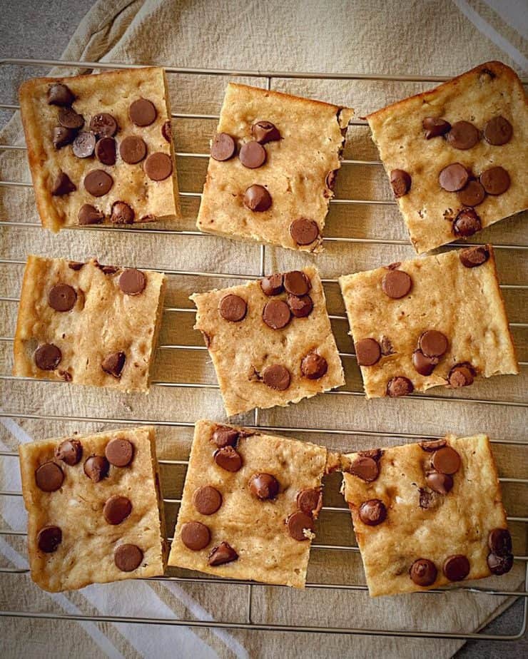 overhead shot of 9 squares of banana chocolate chip healthy breakfast bars on a cooling rack on a tan tea towel