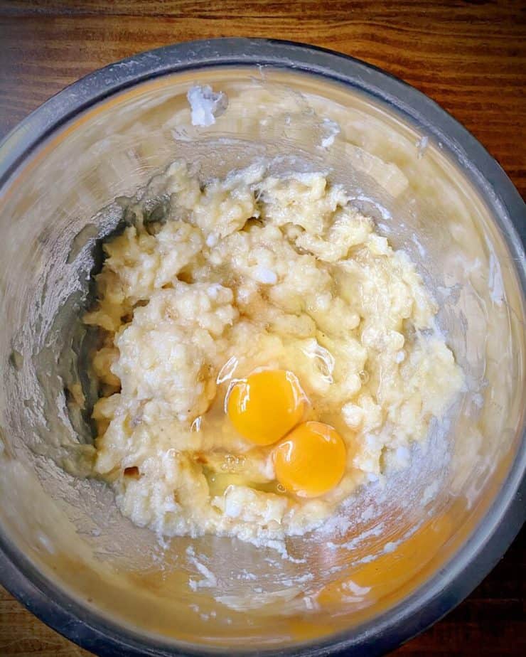 mashed banana, coconut oil with two eggs on top in a metal bowl