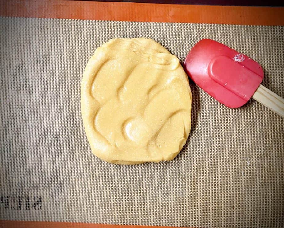 candy corn dough on a silpat lined cookie sheet with a red silicone spatula