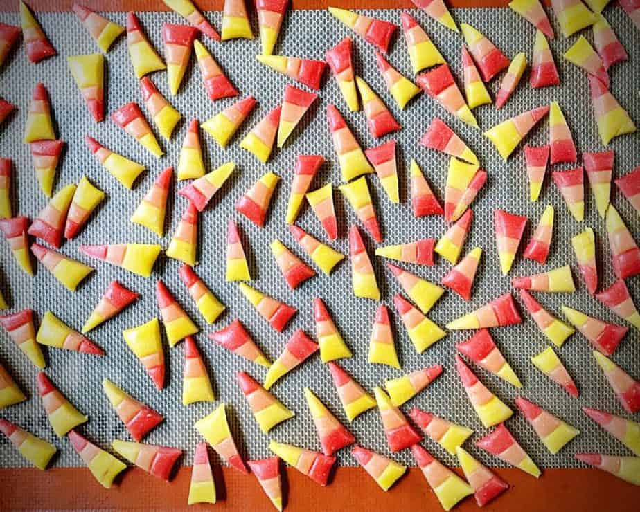 a silpat sheet covered with individual pieces of homemade red, orange and yellow candy corn 