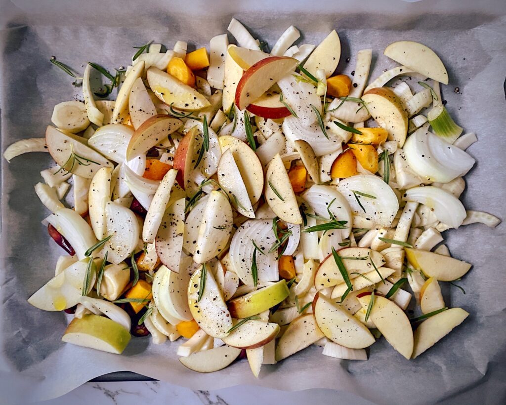 apples, carrots, onions, fennel, rosemary on a parchment lined cookie sheet