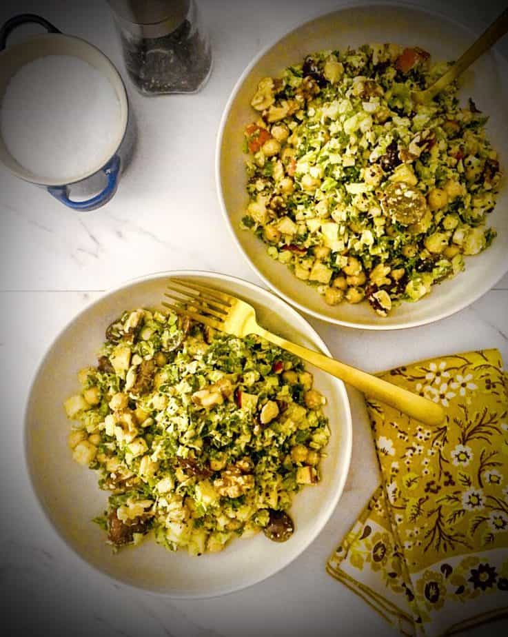 overhead shot of autumn crunch salad from purple carrot in tan pasta bowls with gold forks and yellow floral napkins, a blue salt cellar and a pepper grinder