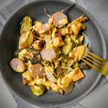 sheet pan sausage and fennel with root vegetables plated in a grey pasta bowl.