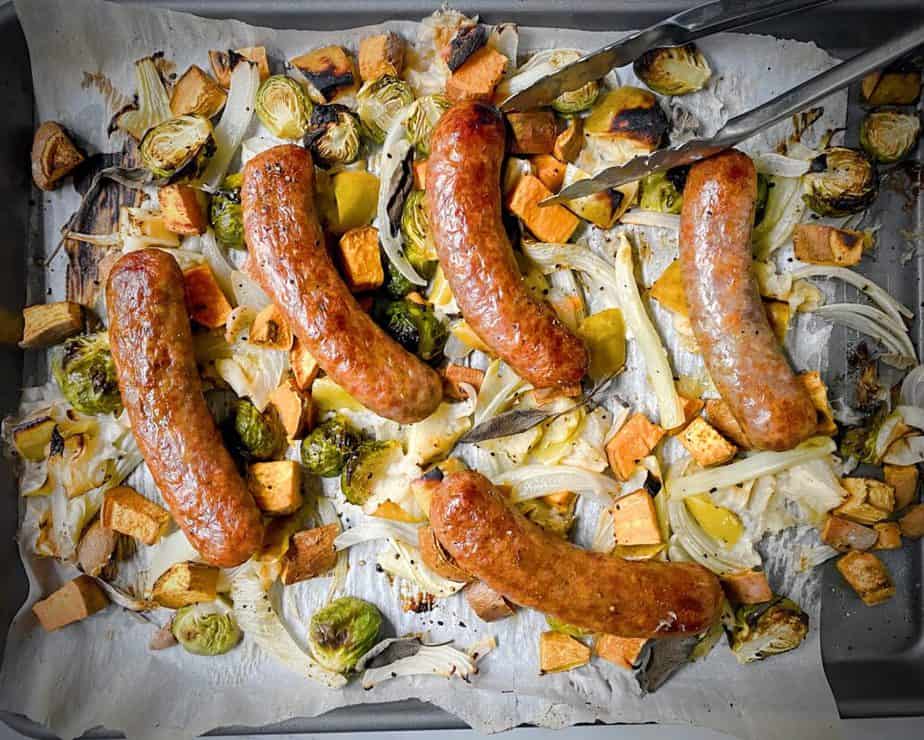 sheet tray loaded up with roasted and charred apples, sweet potatoes, fennel, brussels sprouts, onions and whole sausages