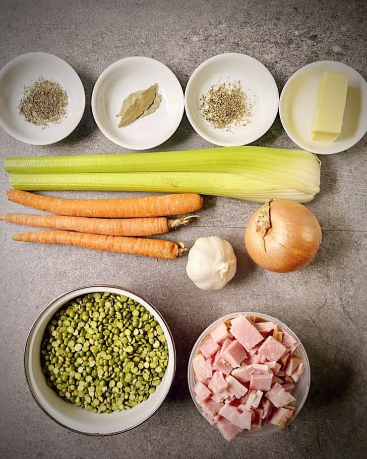 oregano, thyme, bay leaves, butter, 2 celery ribs, 3 carrots, a yellow onion, a head of garlic, chopped ham and split peas as mis en place for split pea and ham soup