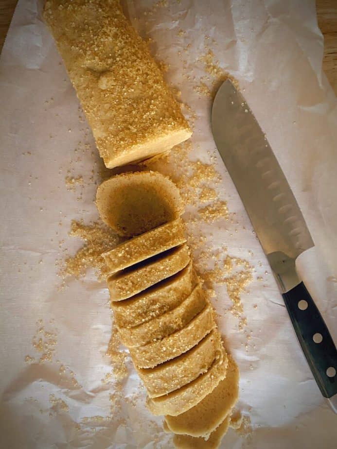 knife on parchment paper with half sliced roll of brown butter dough