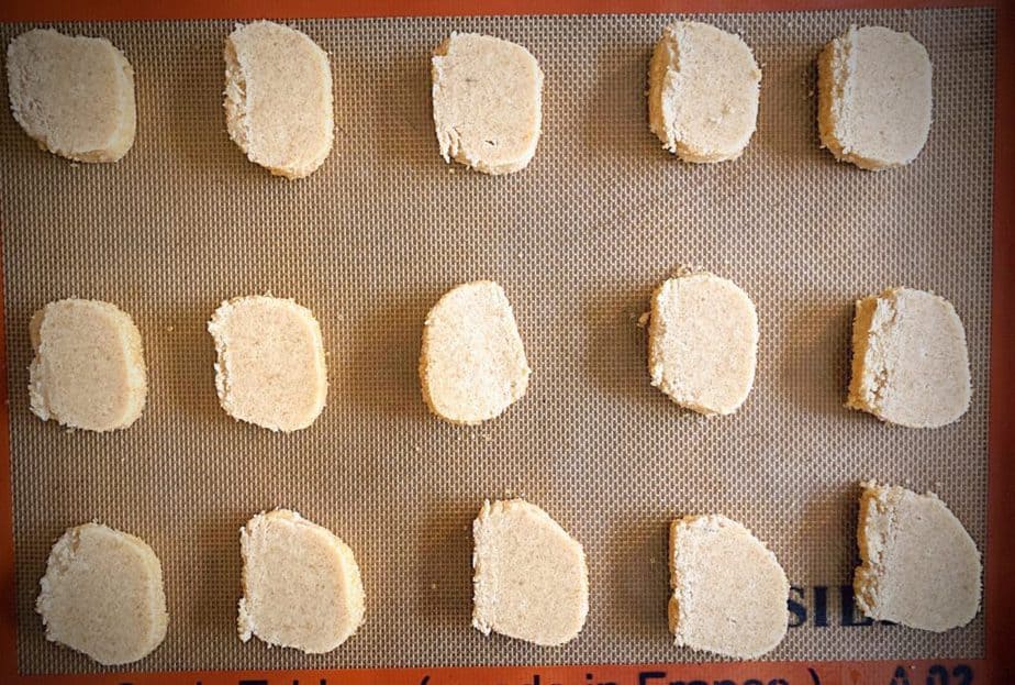 cookie dough slices on a silpat lined baking sheet