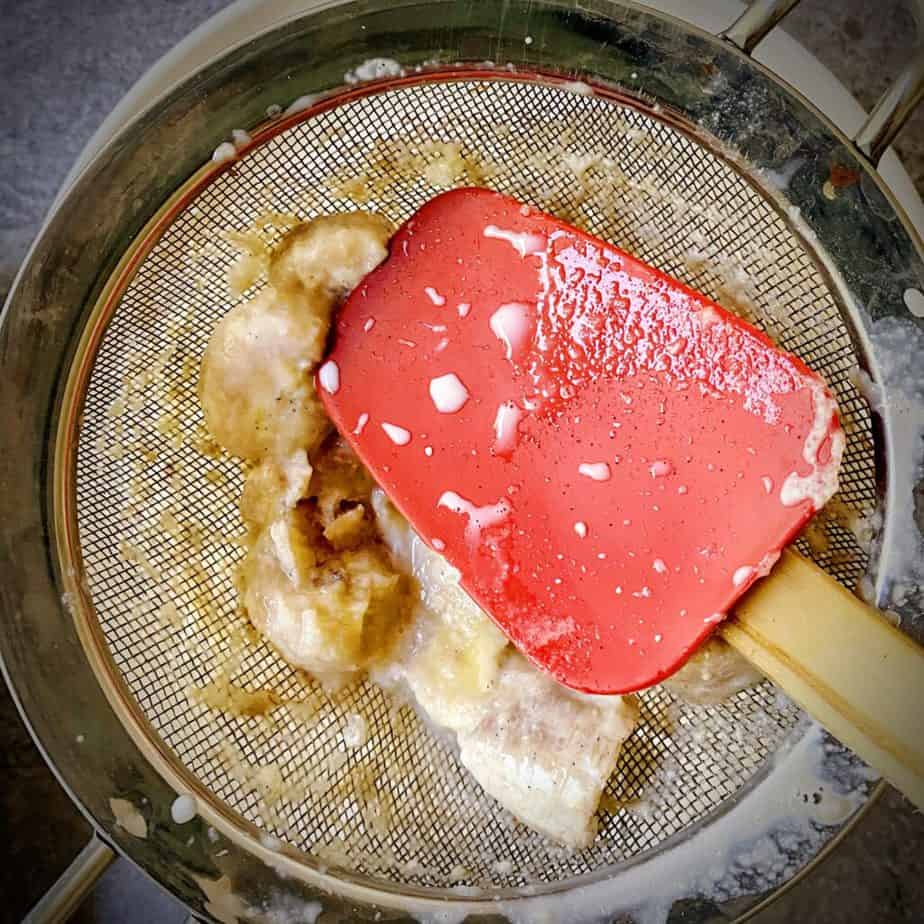 red silicone spatula gently pressing bananas that were steeped to remove excess liquid
