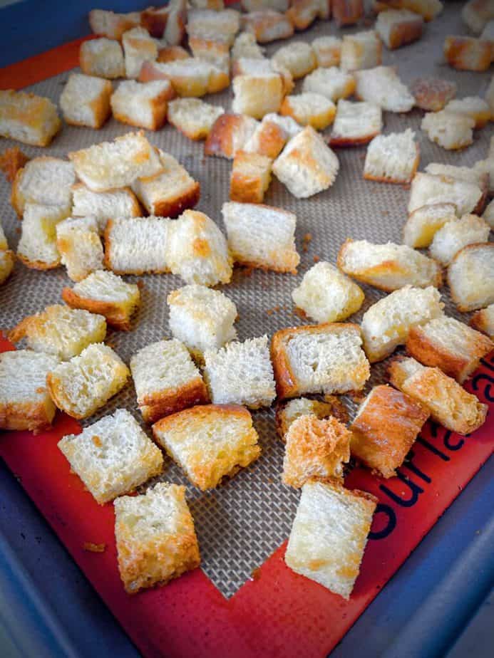 homemade baked croutons after baking on a silpat lined baking sheet