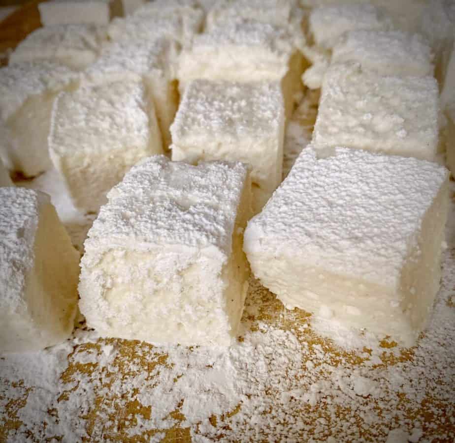 homemade vanilla marshmallows coated in powdered sugar on a wooden surface