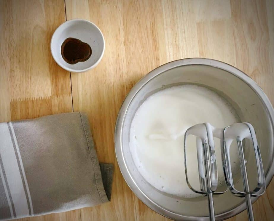 hand beaters showing soft peaked egg whites in a silver bowl