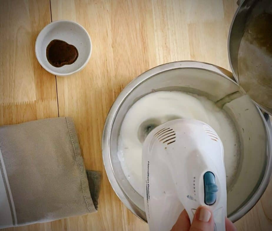 corn syrup sugar mixture being poured into egg white mix with beaters mixing