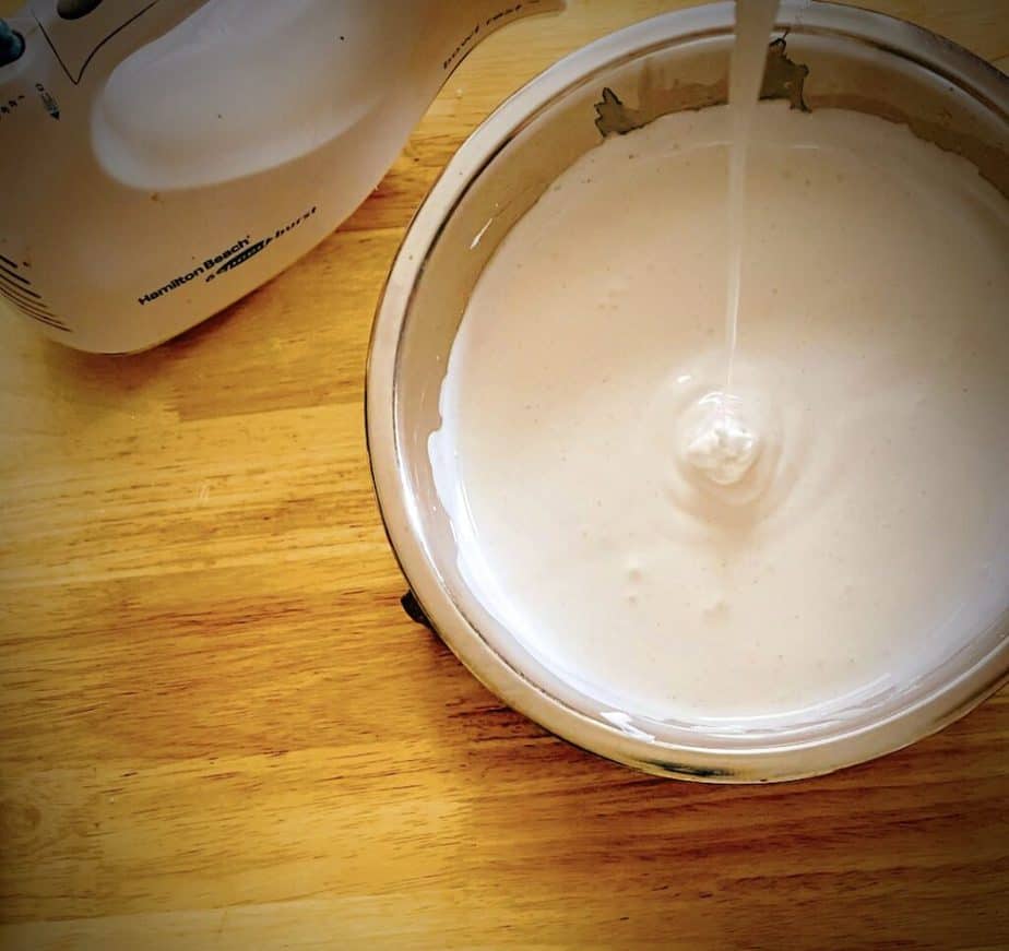 overhead shot of finished marshmallow mix dropping from beater into mixing bowl