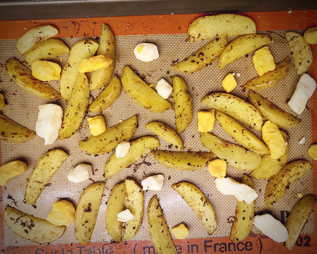 sheet pan potato wedges with cheese curds prior to melting