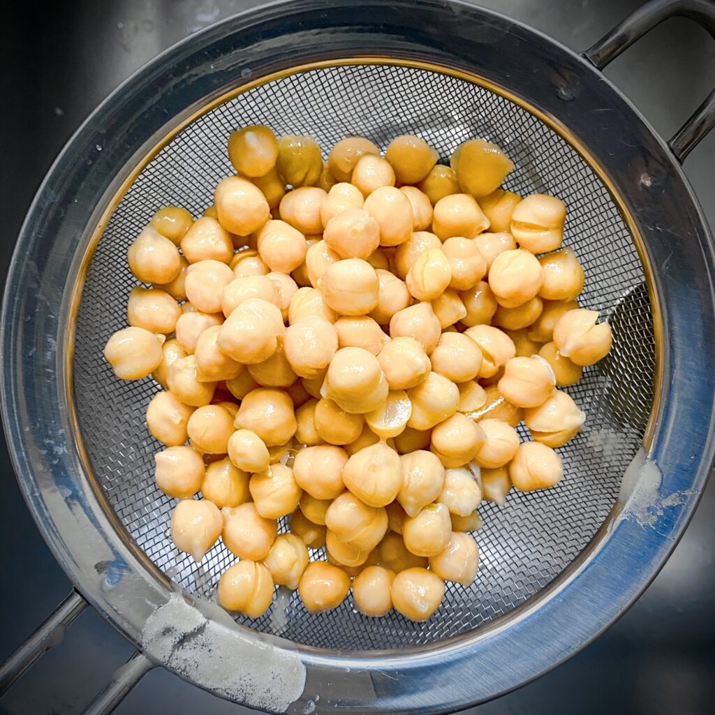 canned chickpeas draining in a mesh strainer 