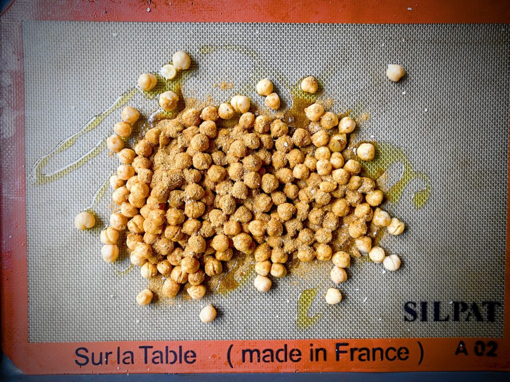 drained chickpeas on a silpat lined cookie sheet that have been drizzled with olive oil and tandoori spices