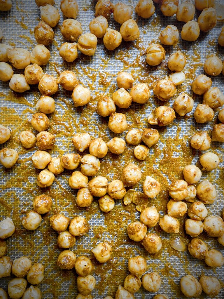 close up of chickpeas tossed with olive oil and tandoori spices on a silpat lined sheet pan