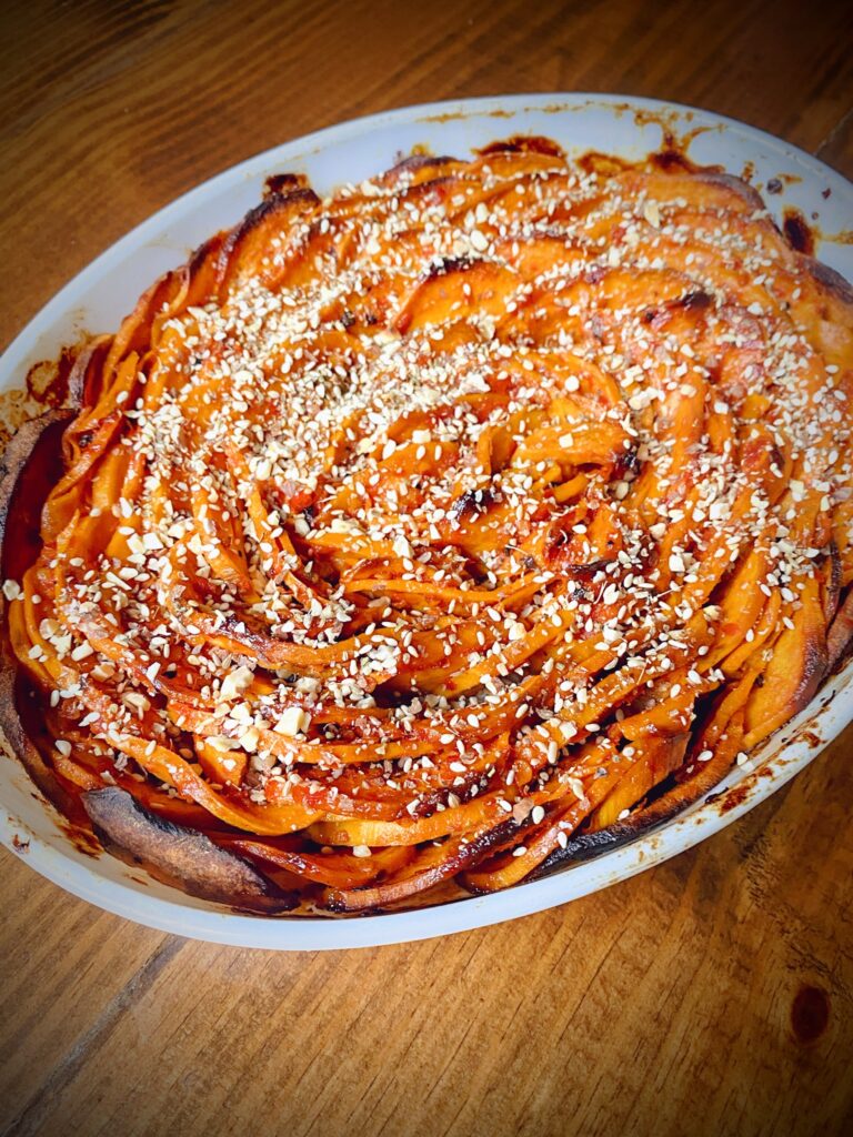 completed maple harissa sweet potato tian with dukkah topping in a white casserole dish