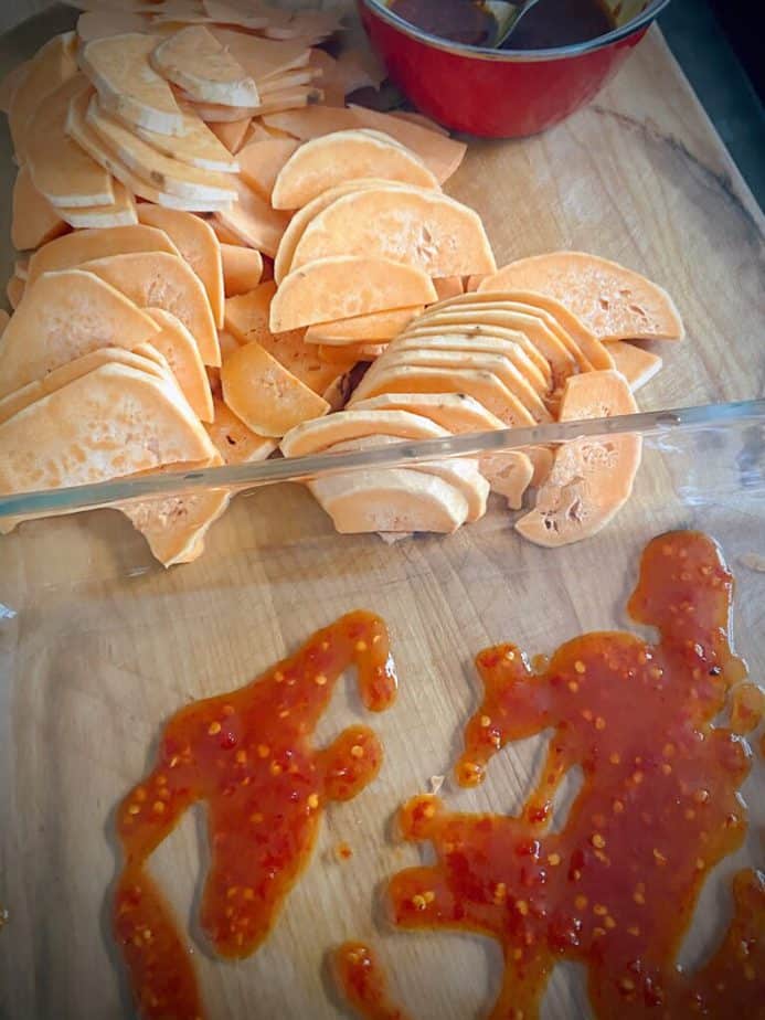 harissa maple sauce in bottom of 9 x 13 pan with sweet potato slices to the side