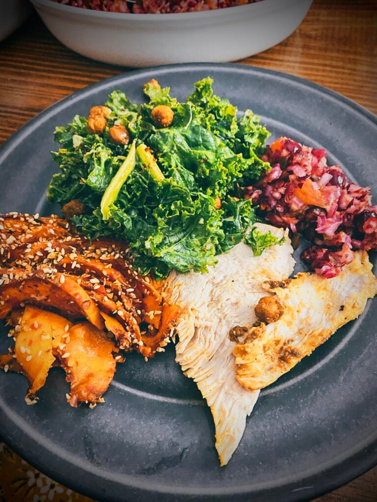 tandoori roasted turkey breast with harissa maple sweet potato tian, kale and chickpea salad and cranberry jalapeño relish on grey plate