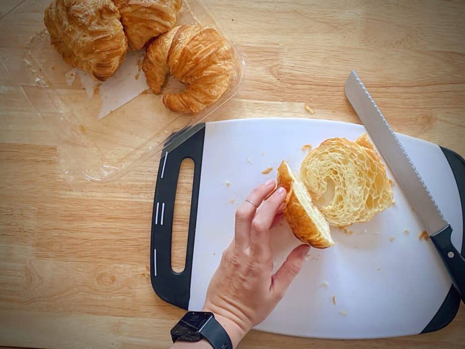 hand holding croissant that has been sliced like a hamburger bun