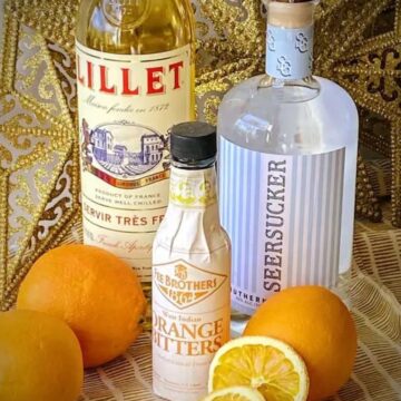 ingredients needed to make abbey cocktails on a table — lillet, gin, and orange bitters.