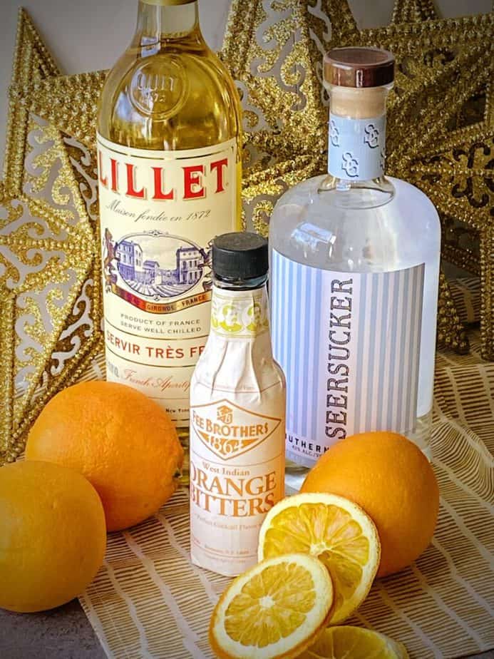 bottles of lillet blanc, seersucker gin, fee brothers orange bitters and fresh oranges for making the abbey cocktail