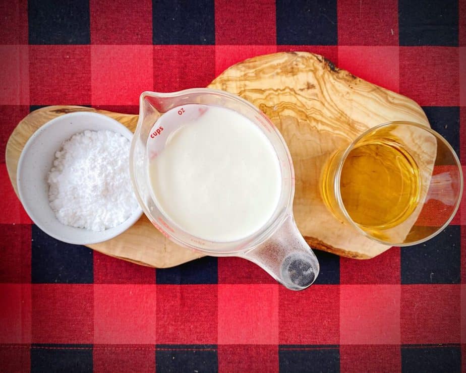 powdered sugar, heavy whipping cream and amaretto as mise en place for amaretto whipped cream on a red and black checked background
