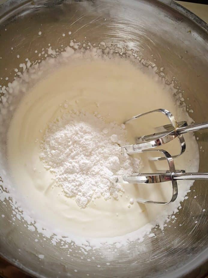 soft peaked whipped cream in a mixing bowl with powdered sugar