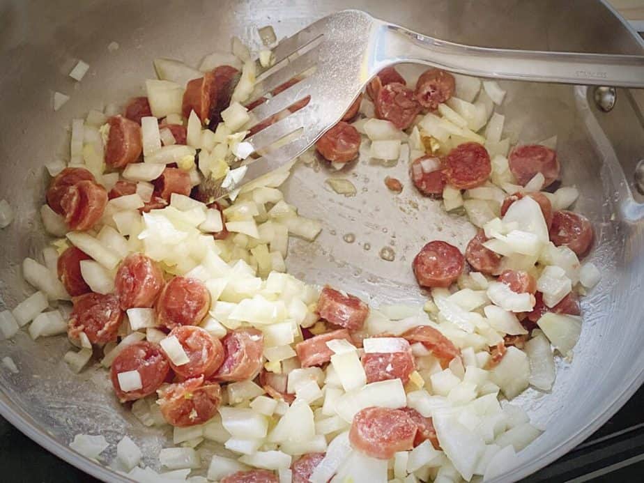 onions and Chinese sausage in a pan after cooking until the onions are beginning to soften