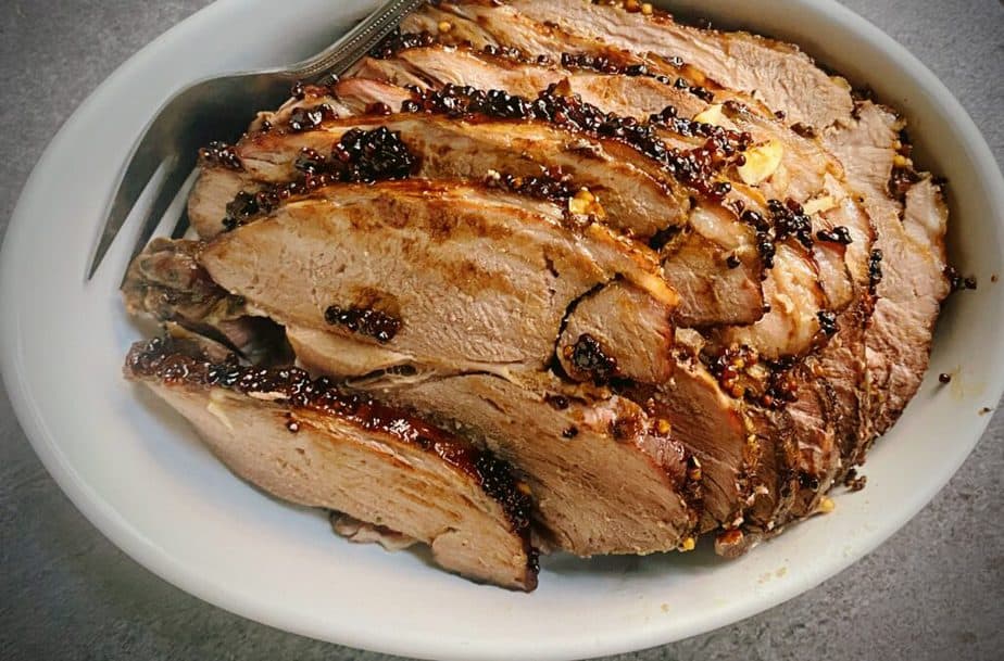 thinly sliced roasted leg of lamb in an oval white serving platter