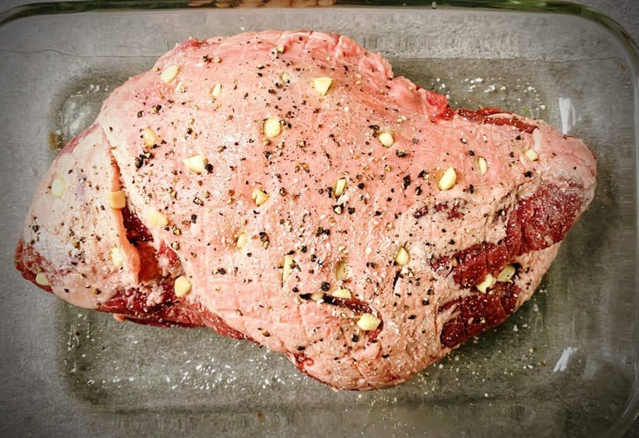 raw leg of lamb roast that has been sprinkled with salt and pepper