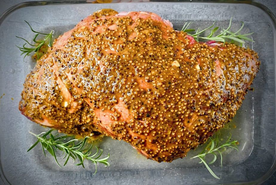 leg of lamb roast with marmite mustard glaze, small pool of white wine and fresh sprigs of rosemary in a 9 x 13