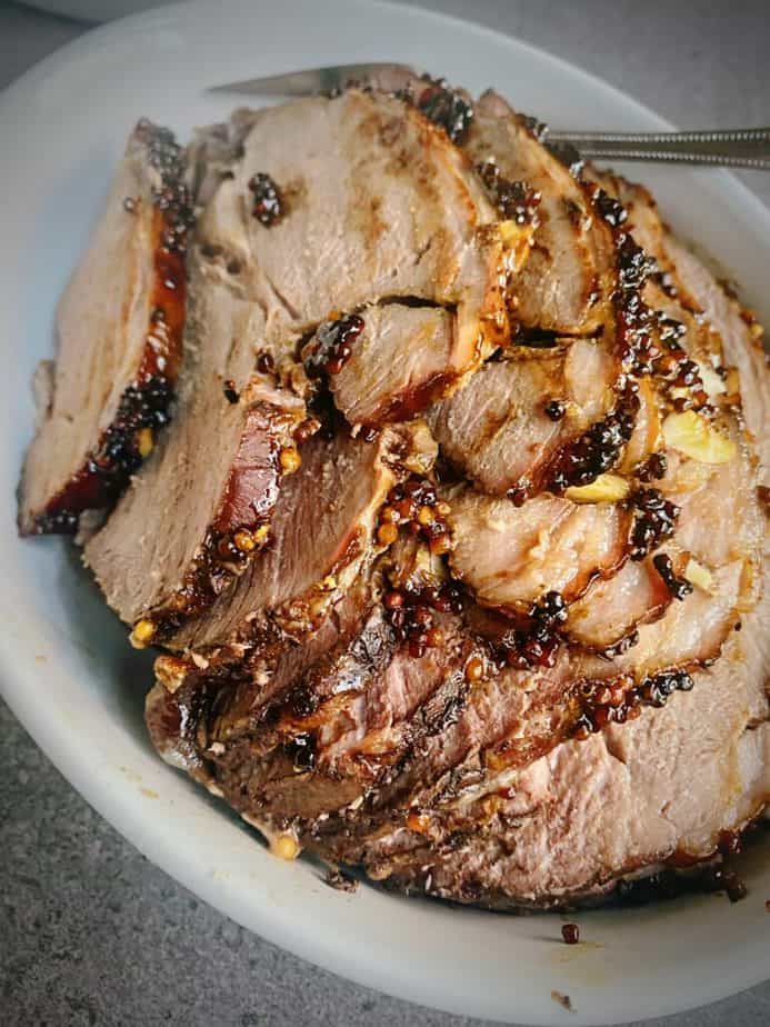 hero shot of roasted leg of lamb that has a marmite mustard seed glaze and is thinly sliced