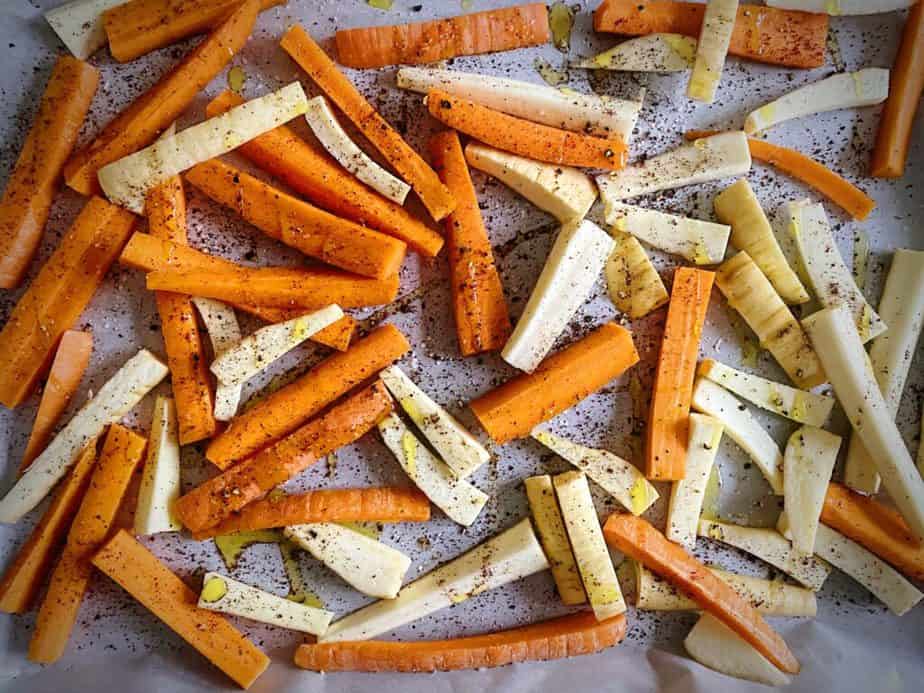 carrot and parsnip matchsticks on a parchment lined sheet pan tossed with olive oil, sumac, salt and pepper