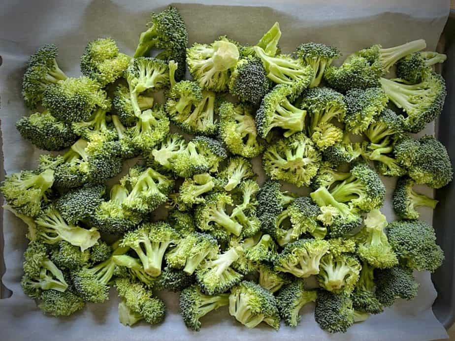 overhead shot of raw broccoli on a parchment lined sheet pan