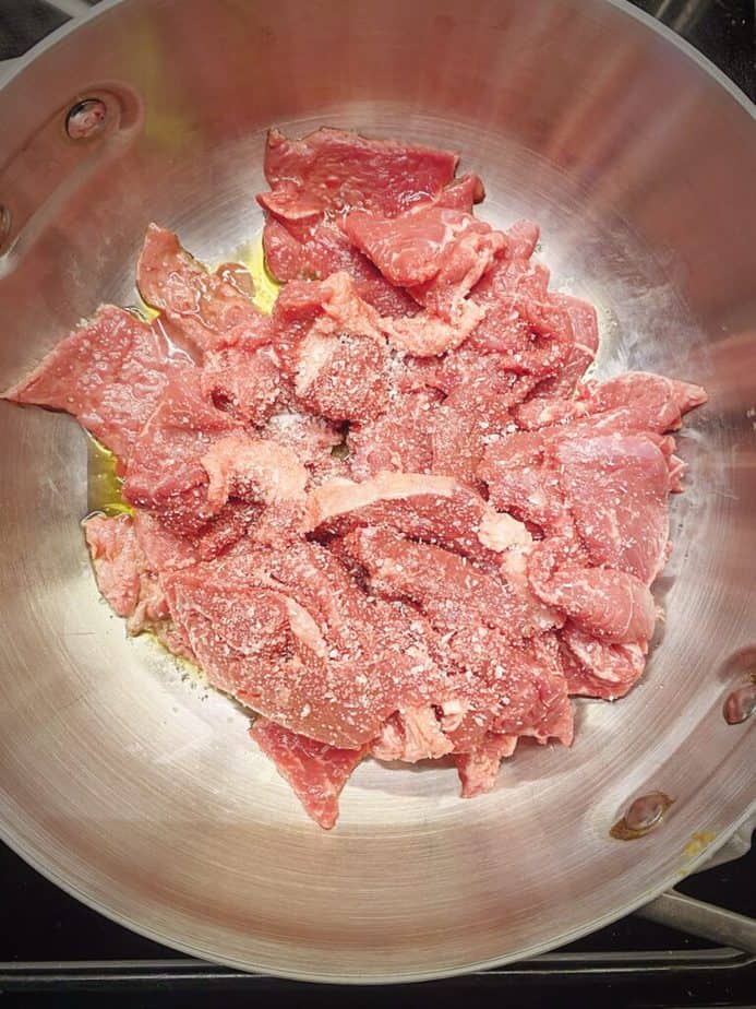 thinly sliced beef just added to sauté pan with seasoning